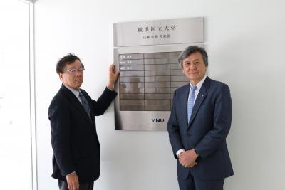 大学の銘板にプレートを設置する藤野 陽三上席特別教授(左)と長谷部 勇一学長(右)