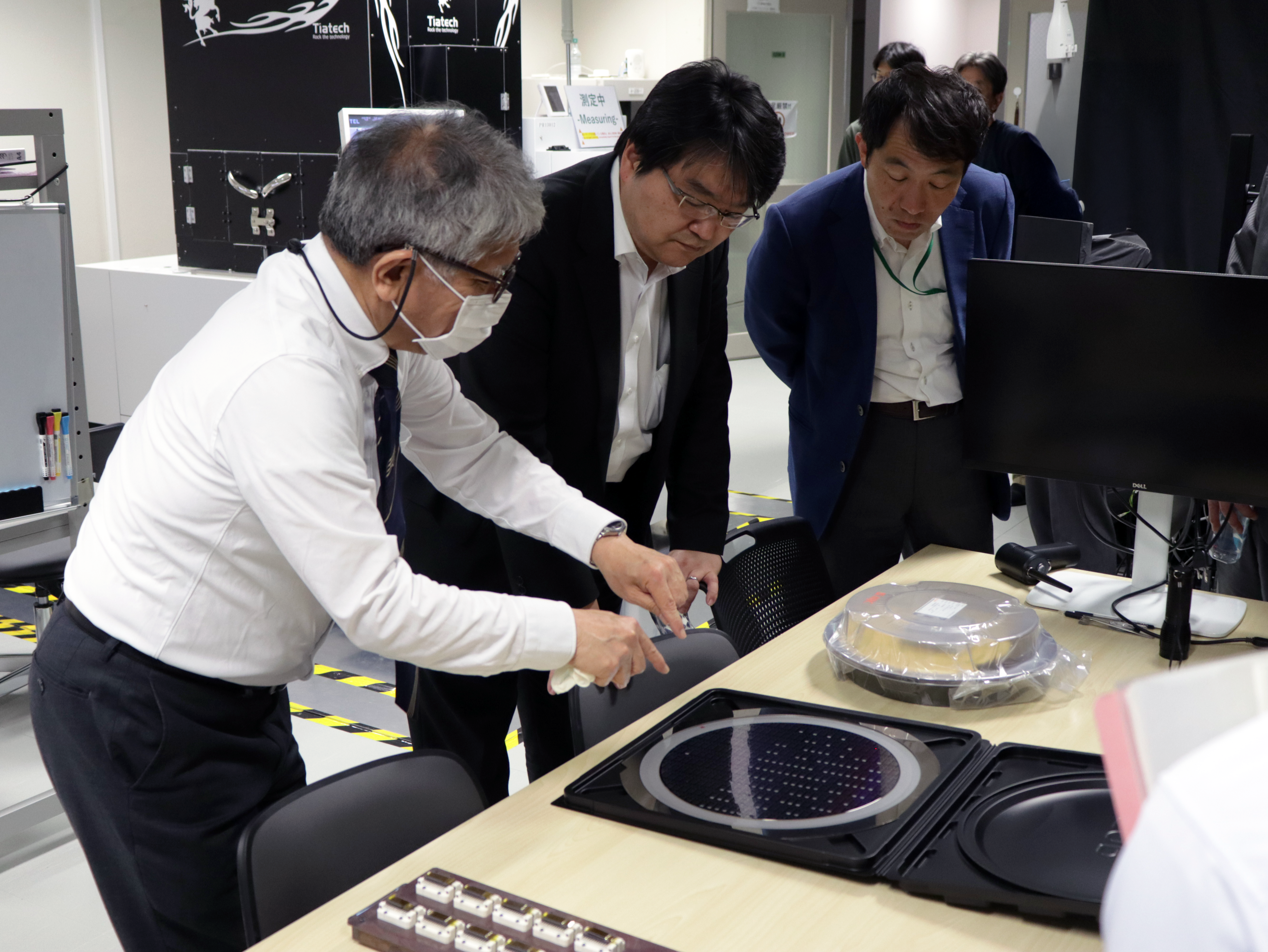 SQIE 上野上席特別教授（左から１人目）から半導体ウェハー評価装置の説明