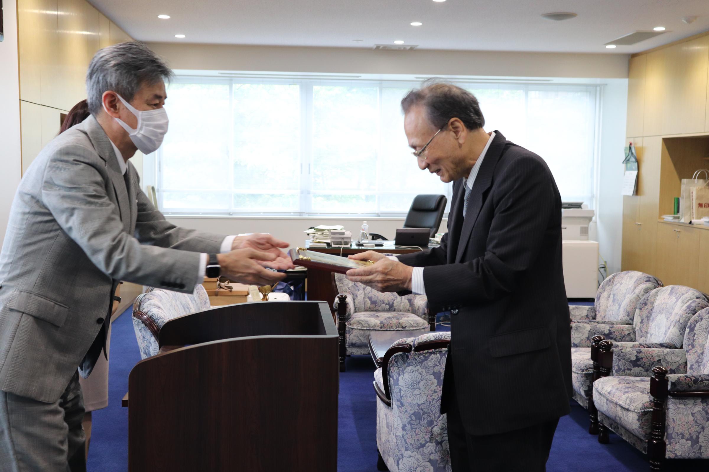 梅原学長より記念盾を受け取る山田様