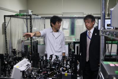 武田教授(左)から量子操作による光ナノ計測について説明を受ける常盤高等教育局長(右)