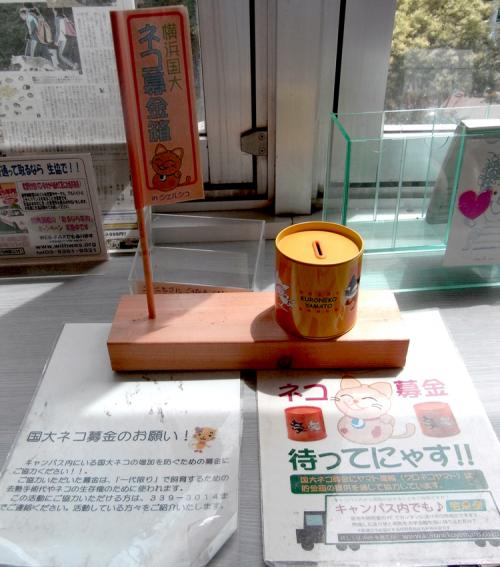小森谷さんが見かけた「国大ネコの募金箱」は、第1食堂れんが館、第2食堂、附属図書館shoca.、大学会館1階購買部、2階シェルシュ、3階きゃら亭の6ヶ所で皆さんの善意を待っています。